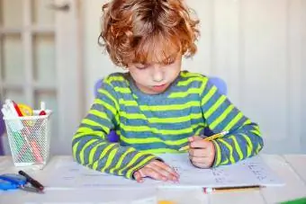 De blonde jongen concentreerde zich thuis op zijn wiskundehuiswerk