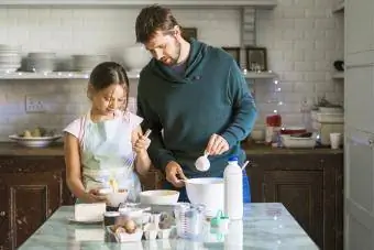 Il padre aiuta la figlia a cucinare in cucina