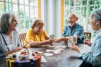 Grupo de personas mayores jugando a las cartas alrededor de la mesa