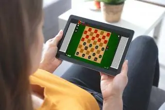 vrouw op tabletcomputer die online damspel speelt