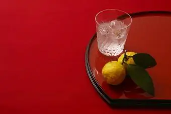 vaso de shochu con yuzu sobre fondo rojo