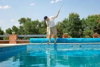 Bărbat care face curățenie la piscină în aer liber