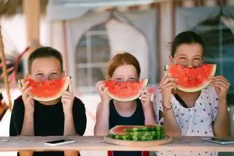 A gyerekek görögdinnyét esznek a tengerparti nyaraláson