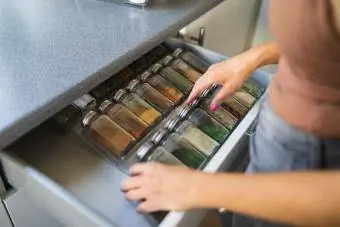 Mga kamay ng babae na nag-aayos ng mga garapon ng pampalasa sa drawer ng kusina