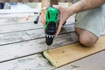 reparar el tornillo de la tabla de la terraza con un taladro eléctrico