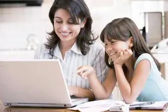 Donna e ragazza in cucina con il computer portatile