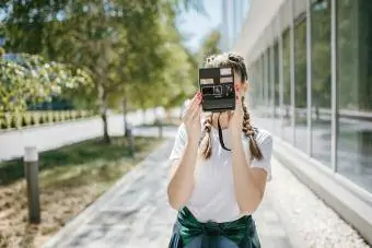 Jauna moteris, naudojanti senovinį polaroidinį fotoaparatą