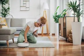 vrouw die haar roomba schoonmaakt