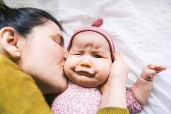 Baby making funny face when mother kiss
