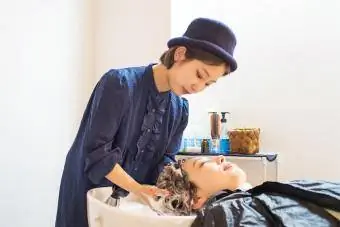 Nastoletni fryzjer myje kobietę szamponem