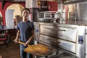 Tizenéves fiú tartja a spatulát a pizzériában