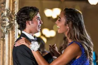 La pareja de adolescentes vestida para la fiesta de graduación, baile lento.