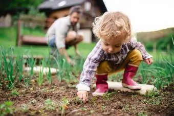 En liten jente med far utendørs hagearbeid