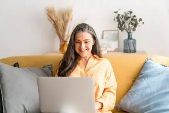 femme plus âgée assise sur un canapé sur son ordinateur portable