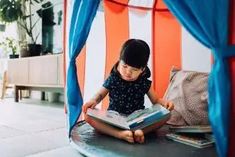 Fetiță care citește o carte în camera ei