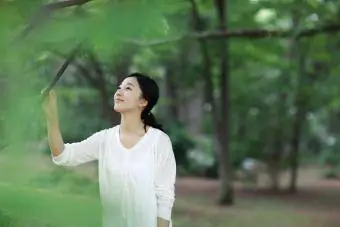 nainen koskettaa puuta puistossa