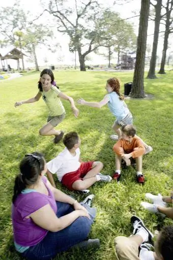 Niños sentados en círculo y jugando pato, pato, ganso.