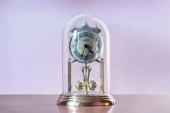 कांच के गुंबद और घूमने वाले पेंडुलम के साथ मेंटल घड़ी