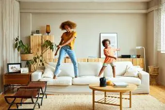 Счастливая мать и сын танцуют дома на диване