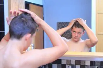 dospívající chlapec, kterým vlasy v zrcadle