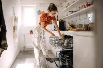 женщина опорожняет посудомоечную машину