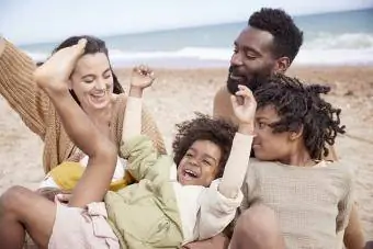 Ģimene pludmalē līksmo ar prieku