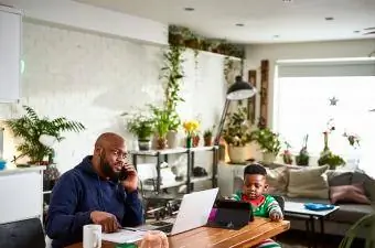 papa assis avec son fils à table pendant qu'ils regardent les appareils