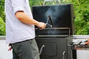 Man Cleaning Grill μπάρμπεκιου με συρμάτινη βούρτσα