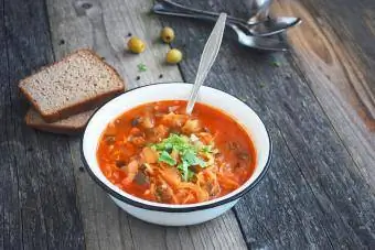 Sopa com repolho, tomate, cogumelos em mesa rústica