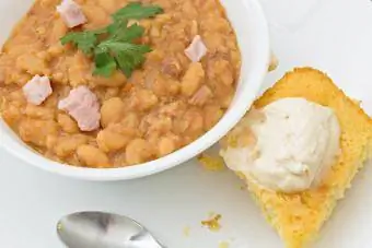 Bol de soupe aux haricots blancs garni de persil vert frais et de morceaux de jambon