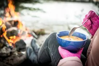 Žena uživa u hrani uz logorsku vatru