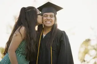 Ragazza che bacia la sorella sulla guancia alla laurea