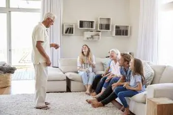 Večgeneracijska družina doma sedi na kavču in igra šarade