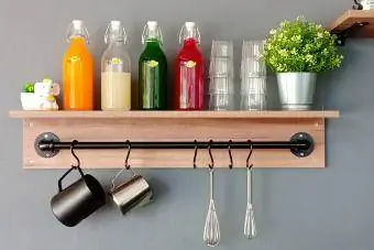 Kleurrijke flessen met glas en bloemen op de plank thuis