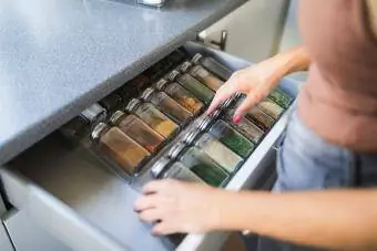 Mãos de mulher arrumando potes de especiarias na gaveta da cozinha