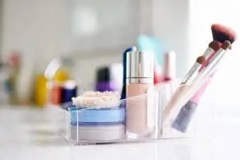Productes de maquillatge i pinzells en recipient de plàstic