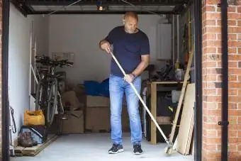 Adam evinin garajının zeminini süpürüyor