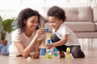Niñera con hijo pequeño juega con bloques de madera