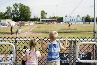 Stadyumdaki çitlerin üzerinden beyzbol maçını izleyen kardeşler