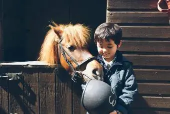 Un giovane ragazzo che tiene un cappello da equitazione