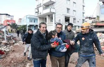 Moški rešujejo otroka po potresu v Turčiji