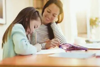 Madre viendo a su hija hacer los deberes