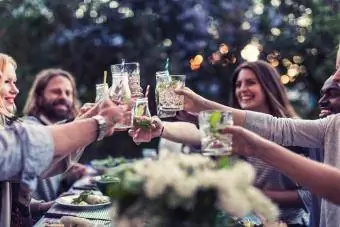 vrienden roosteren aan de eettafel in de tuin