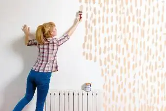 Genç kadın fırçayla duvar boyuyor