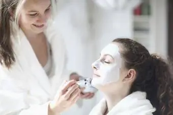 Garota aplicando máscara no rosto de uma amiga