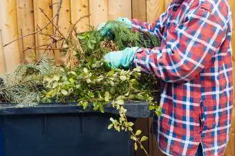 Žena dáva záhradné odrezky do veľkého plastového odpadkového koša
