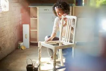 una donna restaura e migliora una vecchia sedia in legno
