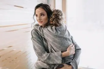 مادر جوان زیبا که فرزند دوست داشتنی خود را در آغوش گرفته است