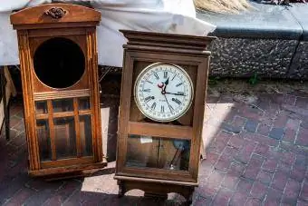 Dos viejos relojes de pared en una caja de madera marrón afuera en la calle