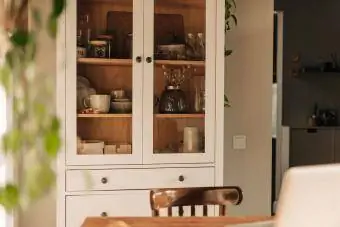 خزانة زجاجية بيضاء مفتوحة مع أطباق وديكور نظيف
